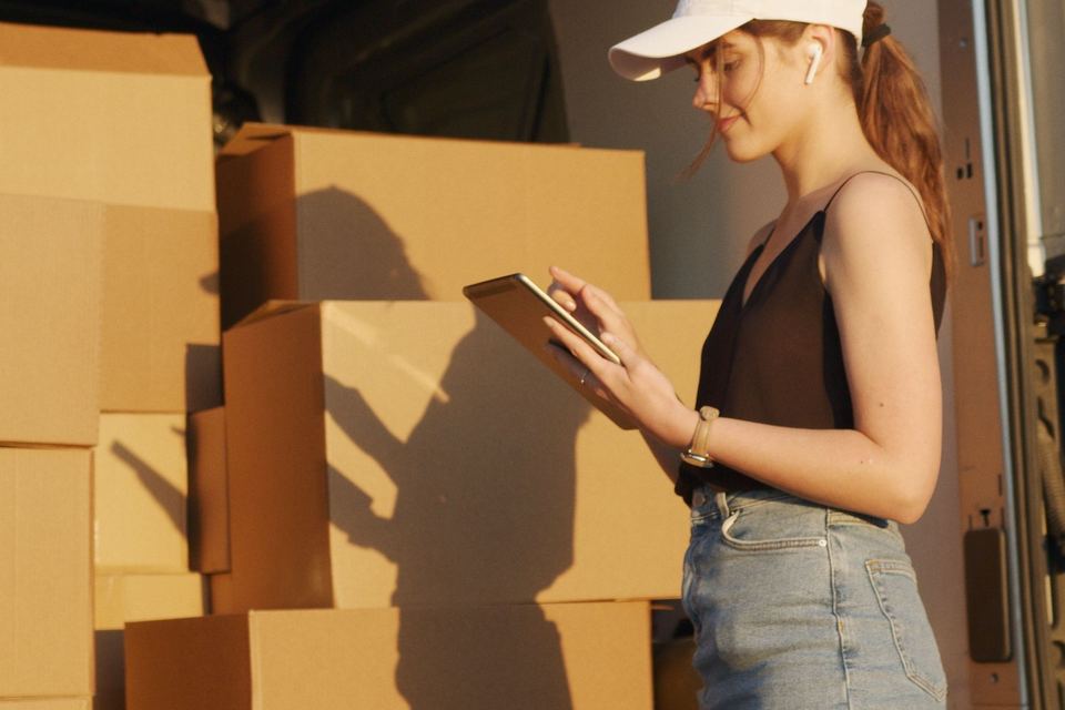 Boxed goods being checked against a list at the back of a delivery vehicle