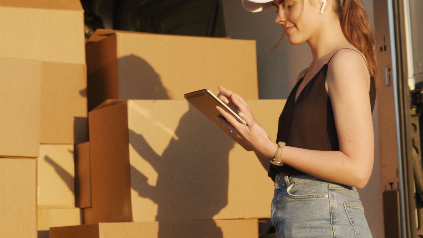 Boxed goods being checked against a list at the back of a delivery vehicle