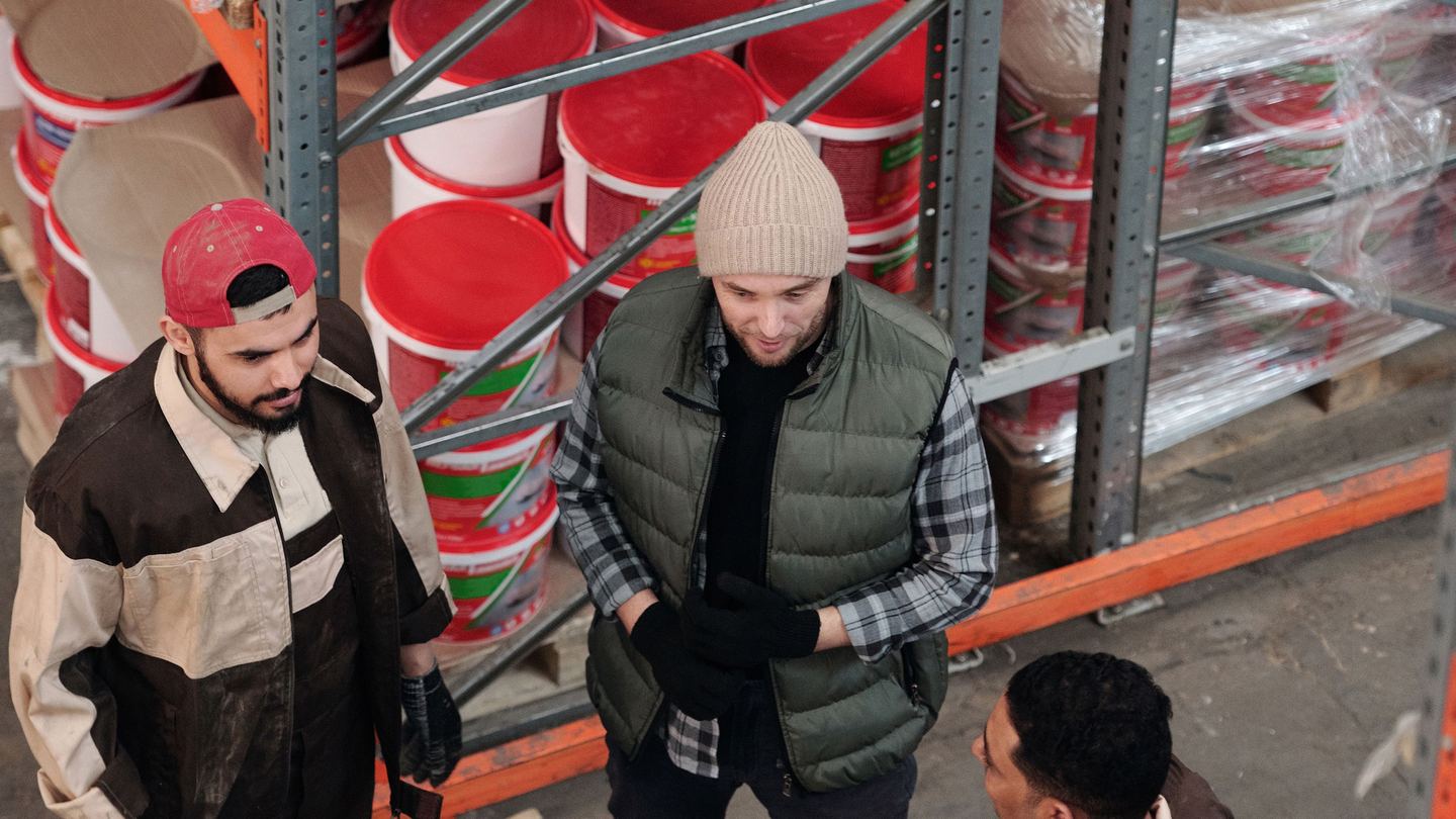 People reviewing stocked goods along a warehouse aisle